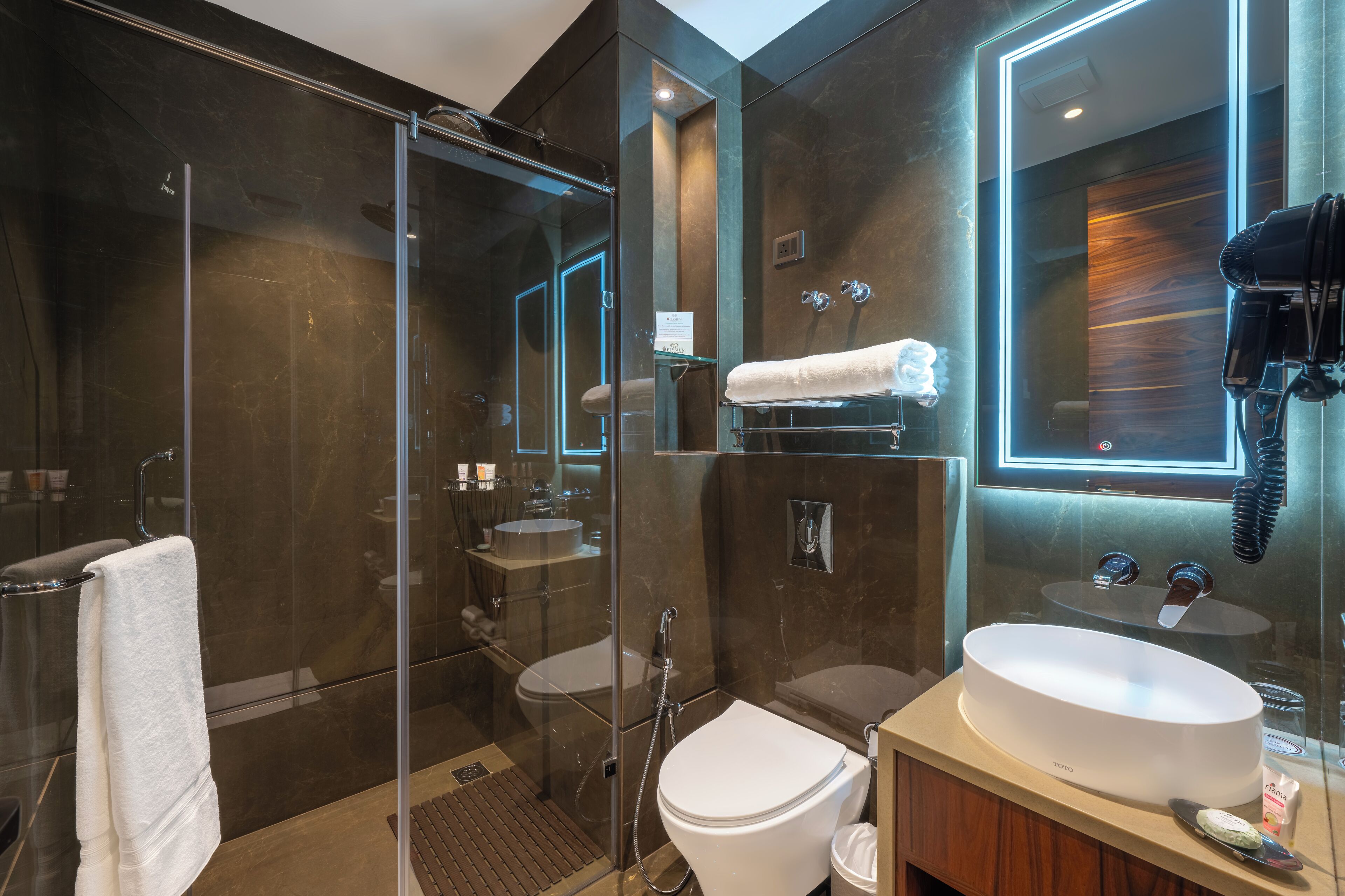 Une salle de bain moderne dotée d’une douche à parois de verre, d’un lavabo blanc et d’un miroir intégrant un téléphone.