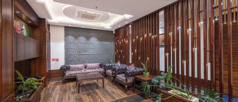 Un moderno vestíbulo con un sofá modular, paneles de madera y una planta grande.