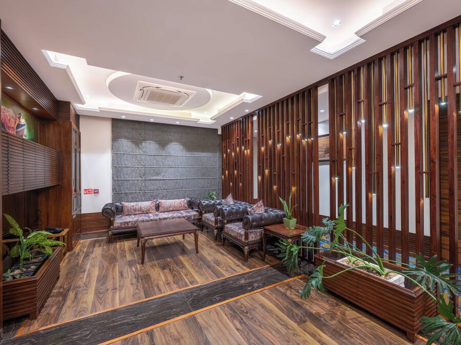 Un hall d’entrée moderne avec un canapé modulable, des panneaux de bois et une grande plante.