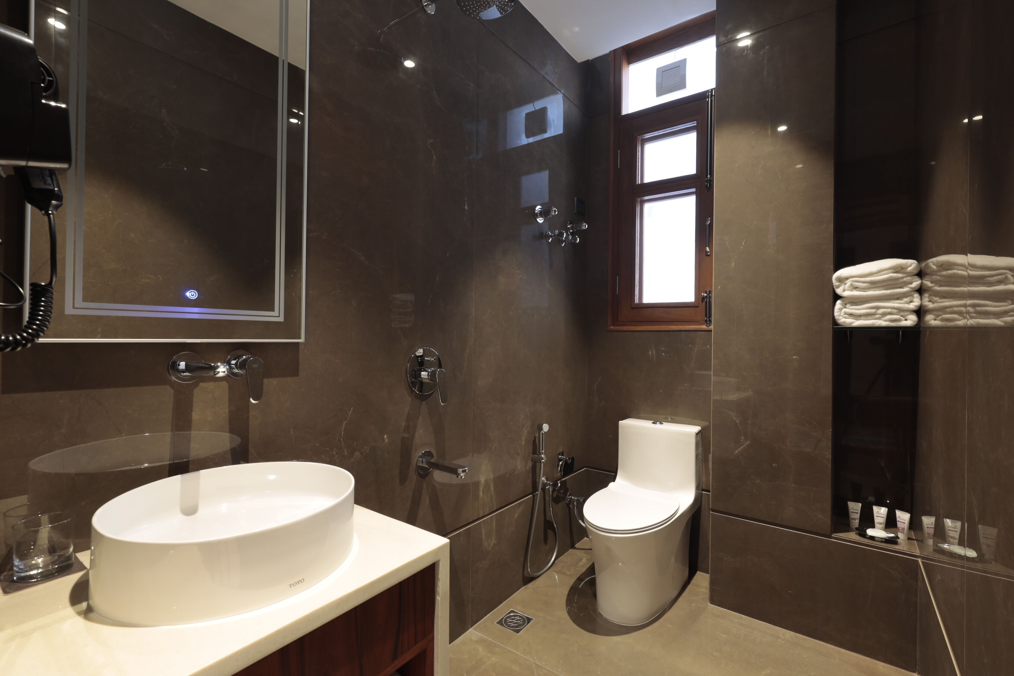 A modern bathroom with a large mirror, a sink, a toilet, and a shower.