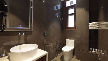 A modern bathroom with a large mirror, a sink, a toilet, and a shower.