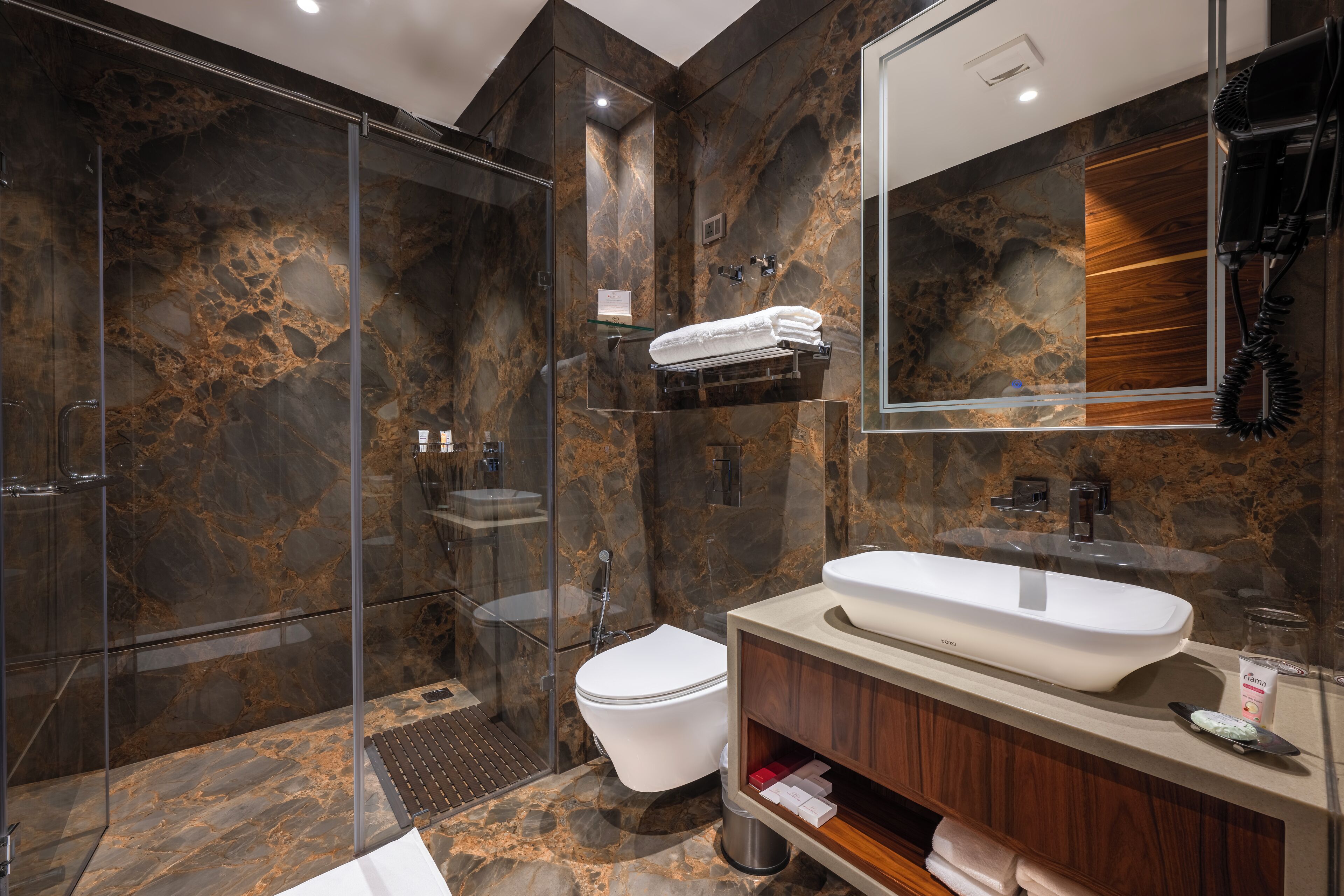 Une salle de bain moderne avec une douche à parois de verre, des toilettes blanches et un meuble-lavabo avec un évier et un miroir.