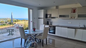 Uma cozinha moderna com armários brancos, forno embutido e uma grande janela com vista panorâmica.