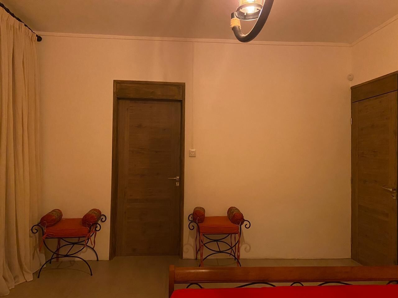 A room with two chairs, a wooden door, and a bed.