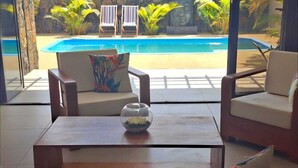 Una stanza con vista su una piscina, due poltrone da relax e un tavolino con una ciotola decorativa.