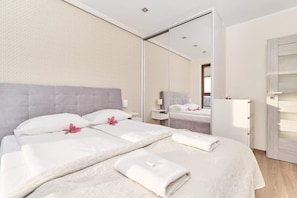 A hotel room with a large bed, a mirror, a wardrobe, and a bedside table.
