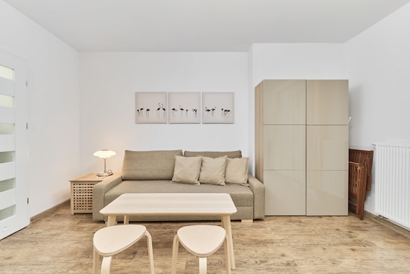 A minimalist living room with a sofa, a table, two chairs, a lamp, and a wardrobe.