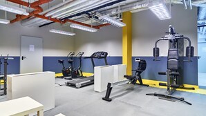 Un gimnasio con equipo de ejercicio, una puerta y una mesa blanca.