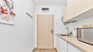 Una cocina estrecha con puerta de madera, microondas y lavabo.