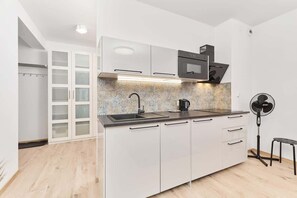 Une cuisine moderne avec des armoires blanches, un plan de travail noir, un four à micro-ondes encastré et un ventilateur.