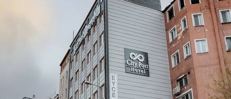 Un hotel con un letrero que dice "City Port Hotel" y "Eye to Tour" en la fachada.