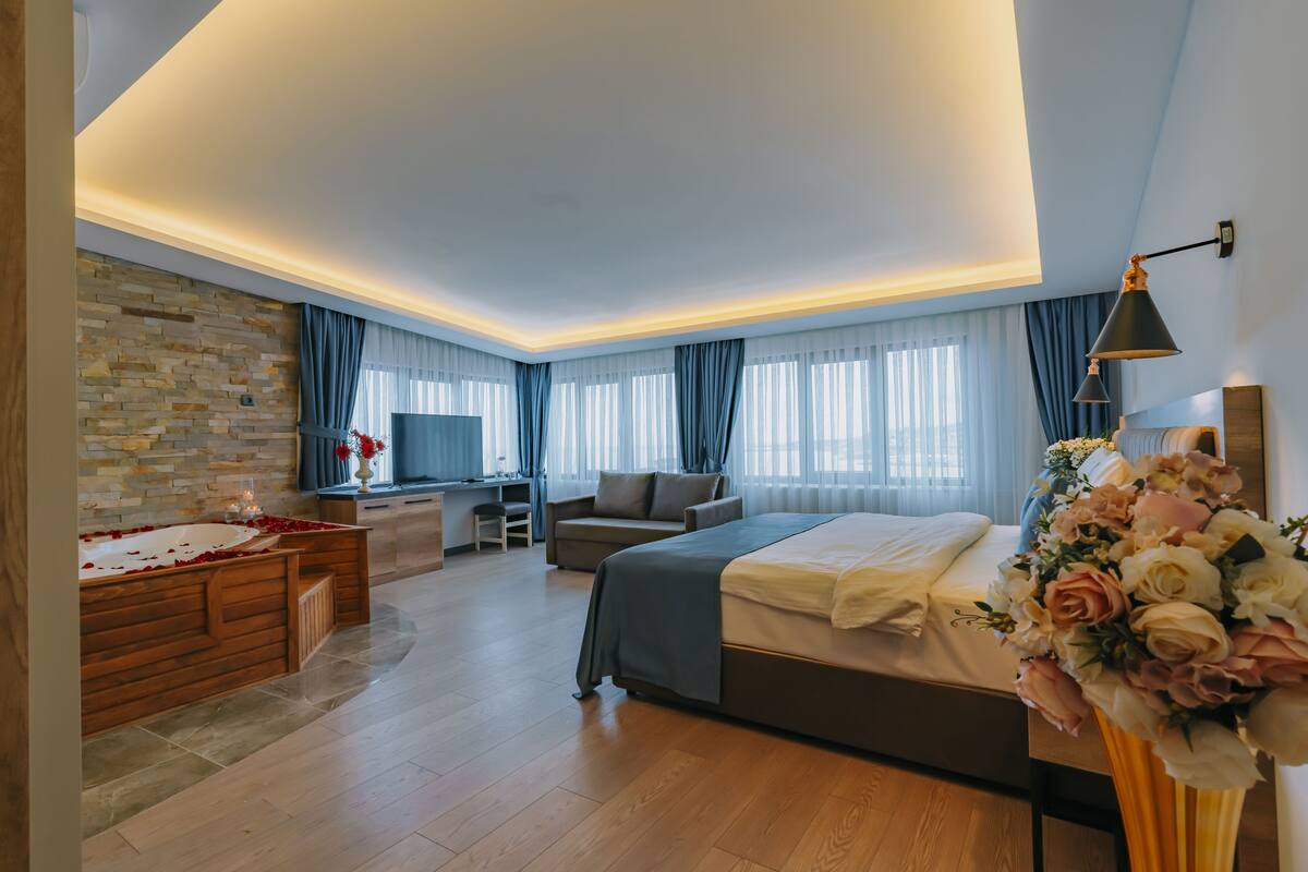 Ett modernt hotellrum med en stor säng, ett skrivbord, en soffa och en TV.