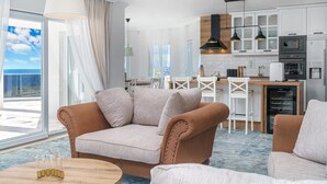 Ein modernes Wohnzimmer mit einer Couch, einem Couchtisch und Blick zur Küche im Hintergrund.
