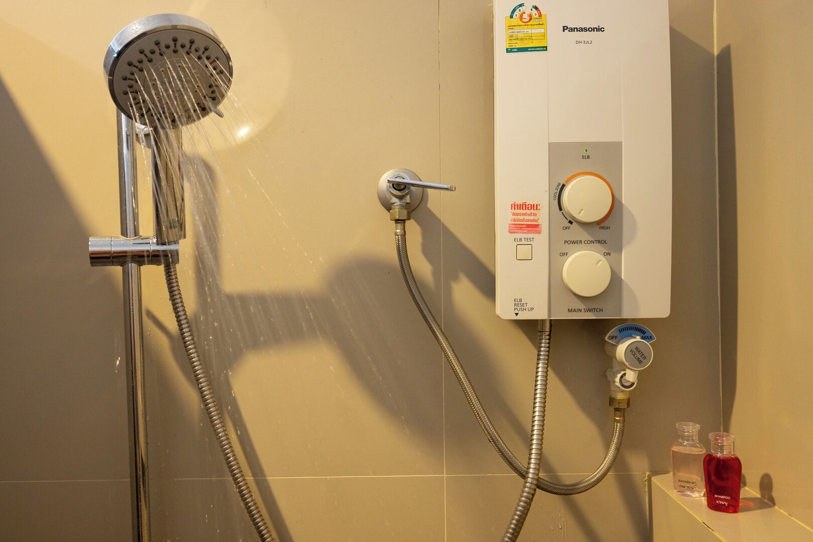 A bathroom with a shower, a control panel, and toiletries.