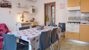 Cocina compacta con comedor, que incluye una mesa con mantel estampado, sillas, estufa y armarios.