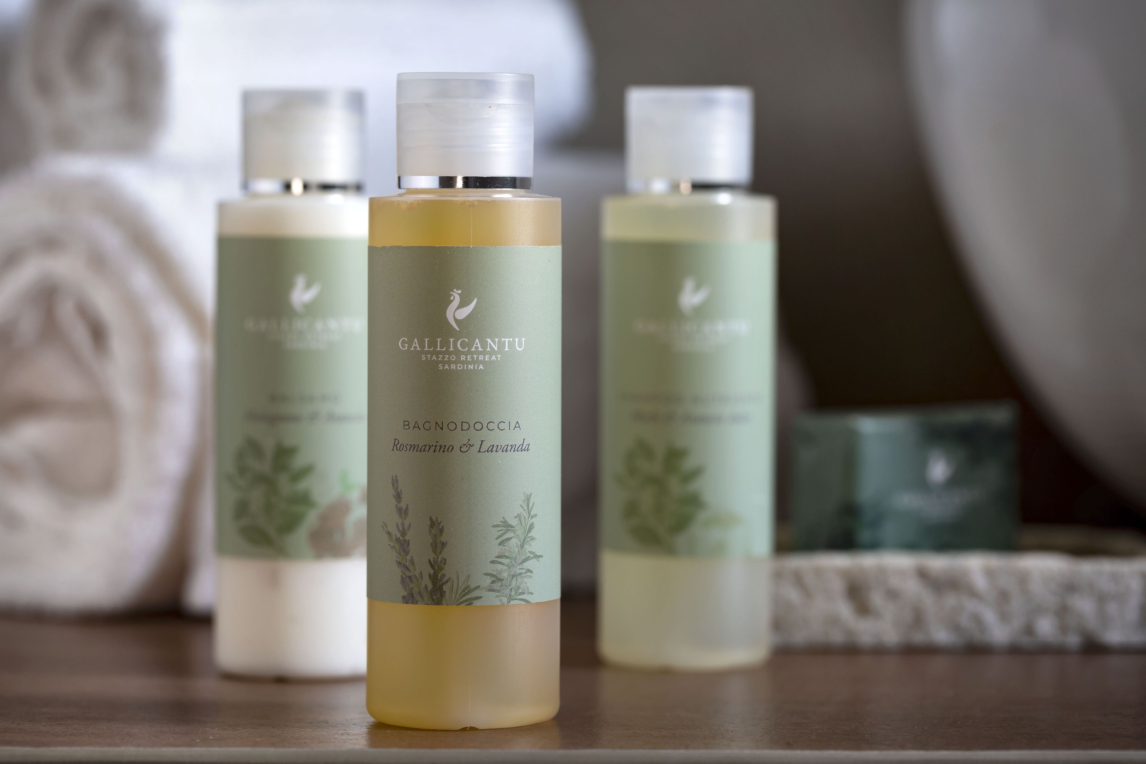 Three bottles of Gallicantu body wash on a wooden surface.