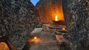 A stone interior with a fire pit and candles, suggesting a rustic setting. - Gallicantu Stazzo Retreat (Luogosanto)