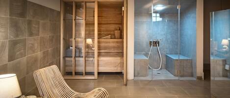 Un baño moderno con ducha, tocador de madera y una silla de mimbre.