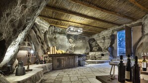 A rustic stone interior with a wooden bar, stone walls, and a thatched roof. - Gallicantu Stazzo Retreat (Luogosanto)