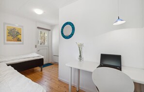 A bedroom with a bed, a desk with a laptop, a chair, a window, and a door. - Nice home in Aakirkeby with WiFi (Aakirkeby)