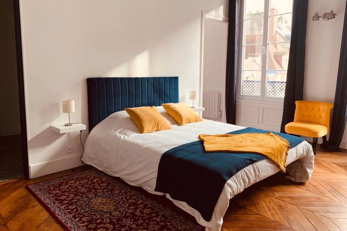 A bedroom with a bed, a nightstand, a chair, and a window.