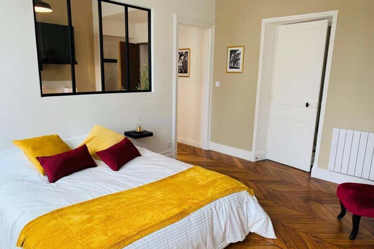 A bedroom with a large bed, a nightstand, a mirror, and a door.