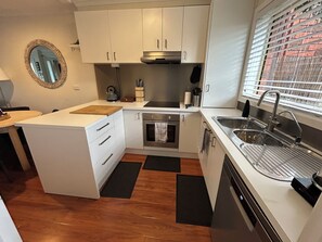 Enjoy cooking in this well-equipped kitchen with a central island, white cabinetry, and stainless steel appliances.