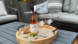 En bricka i trä med en flaska Bellarine Rosévin, två glas och en skål med oliver på ett bord.