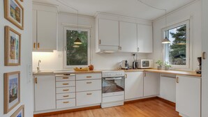 A modern kitchen with white cabinets, a stove, a microwave, and wooden countertops. - Awesome home in Nexø with WiFi (Nexø)