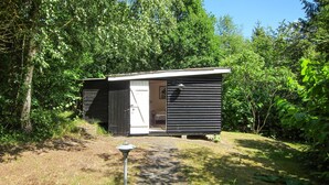 A small, single-room cabin with a door and a window, surrounded by dense greenery. - Stunning home in Aakirkeby with WiFi (Aakirkeby)