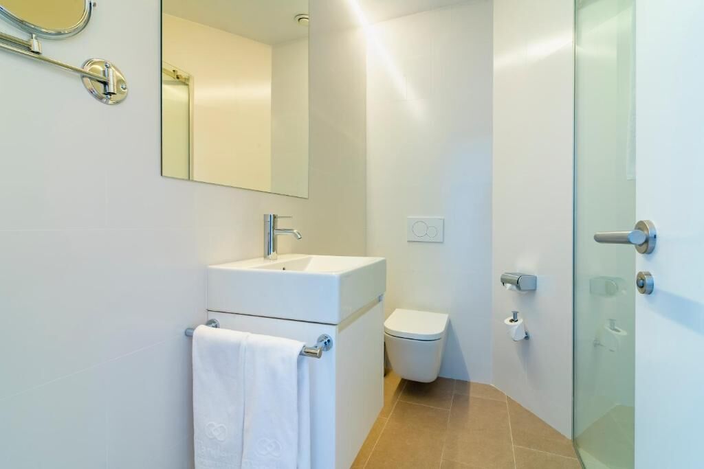 A modern bathroom with a white sink, toilet, and glass shower enclosure.