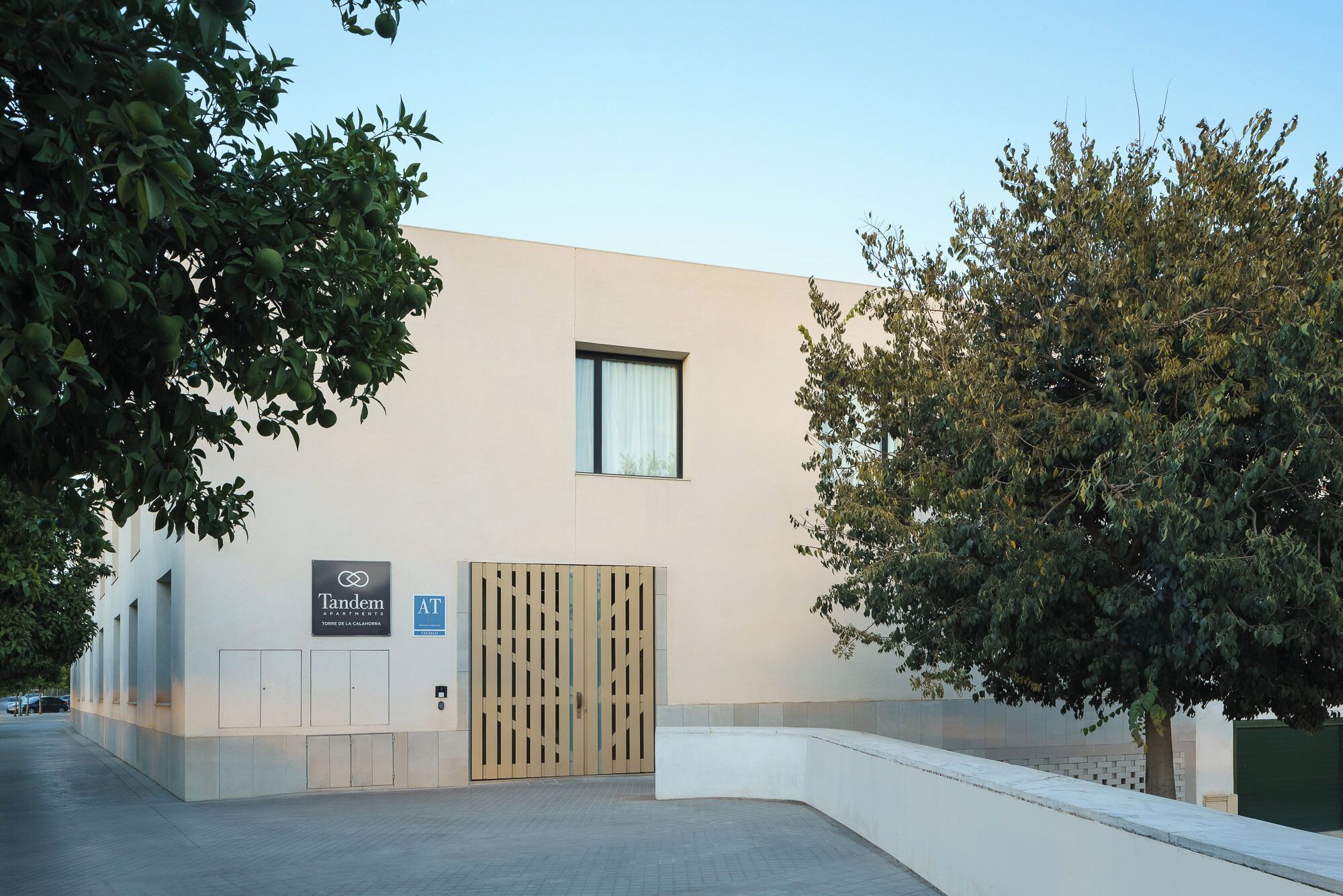 A modern building with a flat facade, a single window, and a gated entrance.