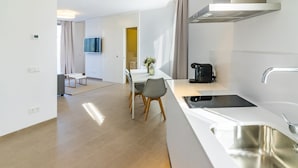 Een moderne keuken met een roestvrijstalen spoelbak, een ingebouwde kookplaat en een eethoek met een tafel en stoelen.