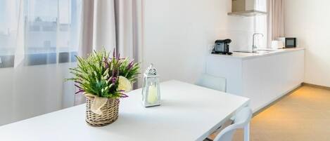 A modern kitchen with a white countertop, a coffee machine, and a microwave.