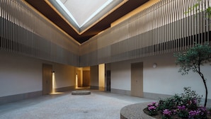 Een ruime atrium met een hoge plafond, inbouwverlichting en een centraal cirkelvormig zitgedeelte.