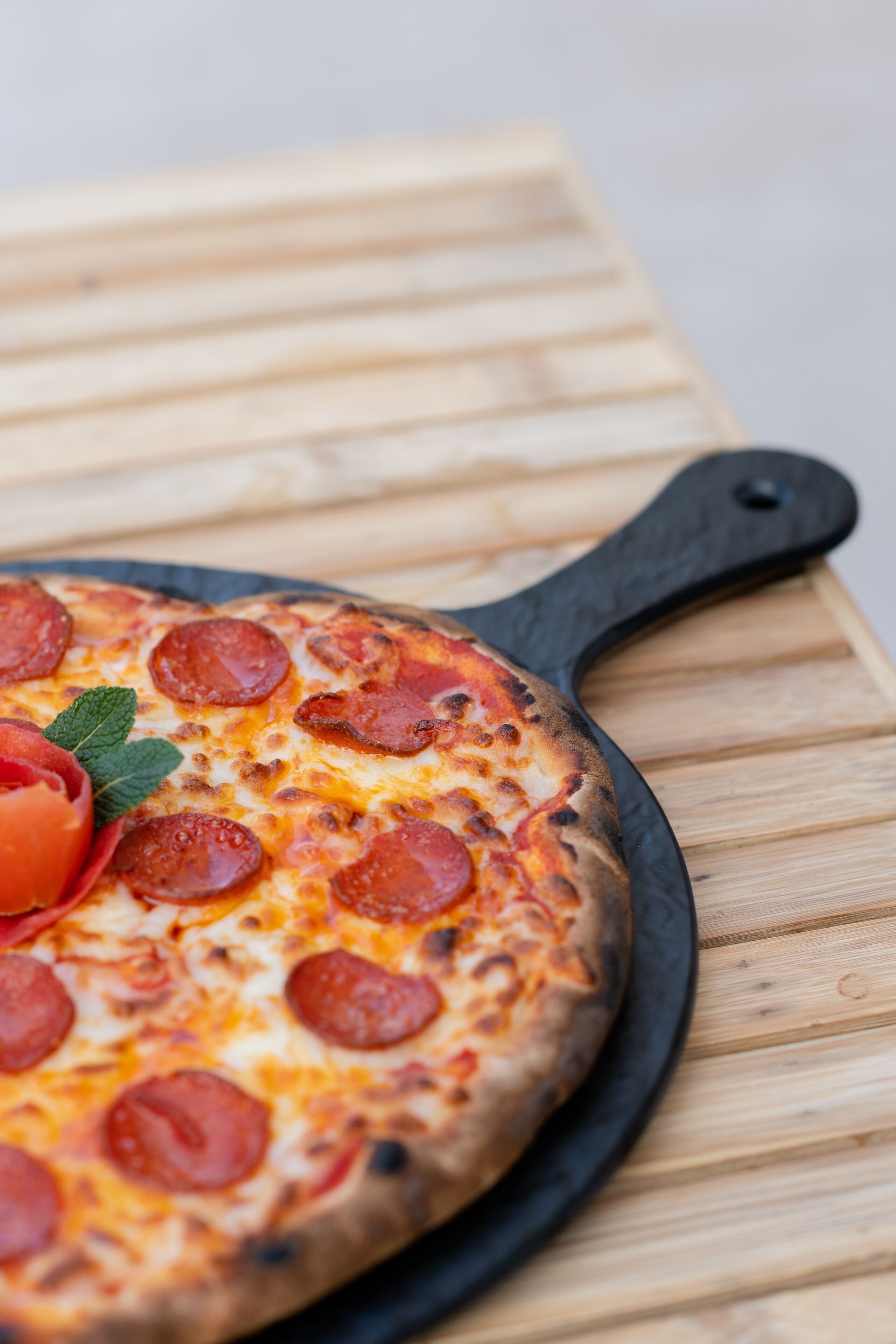 Une pizza sur une poêle noire, posée sur une table en bois.