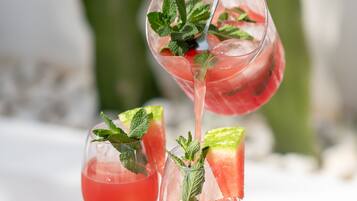 Tres vasos de cóctel rosado con hojas de menta sobre una mesa de madera.