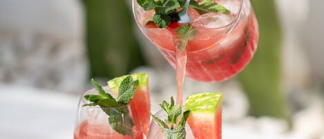 Three glasses of pink cocktail with mint leaves on a wooden table.