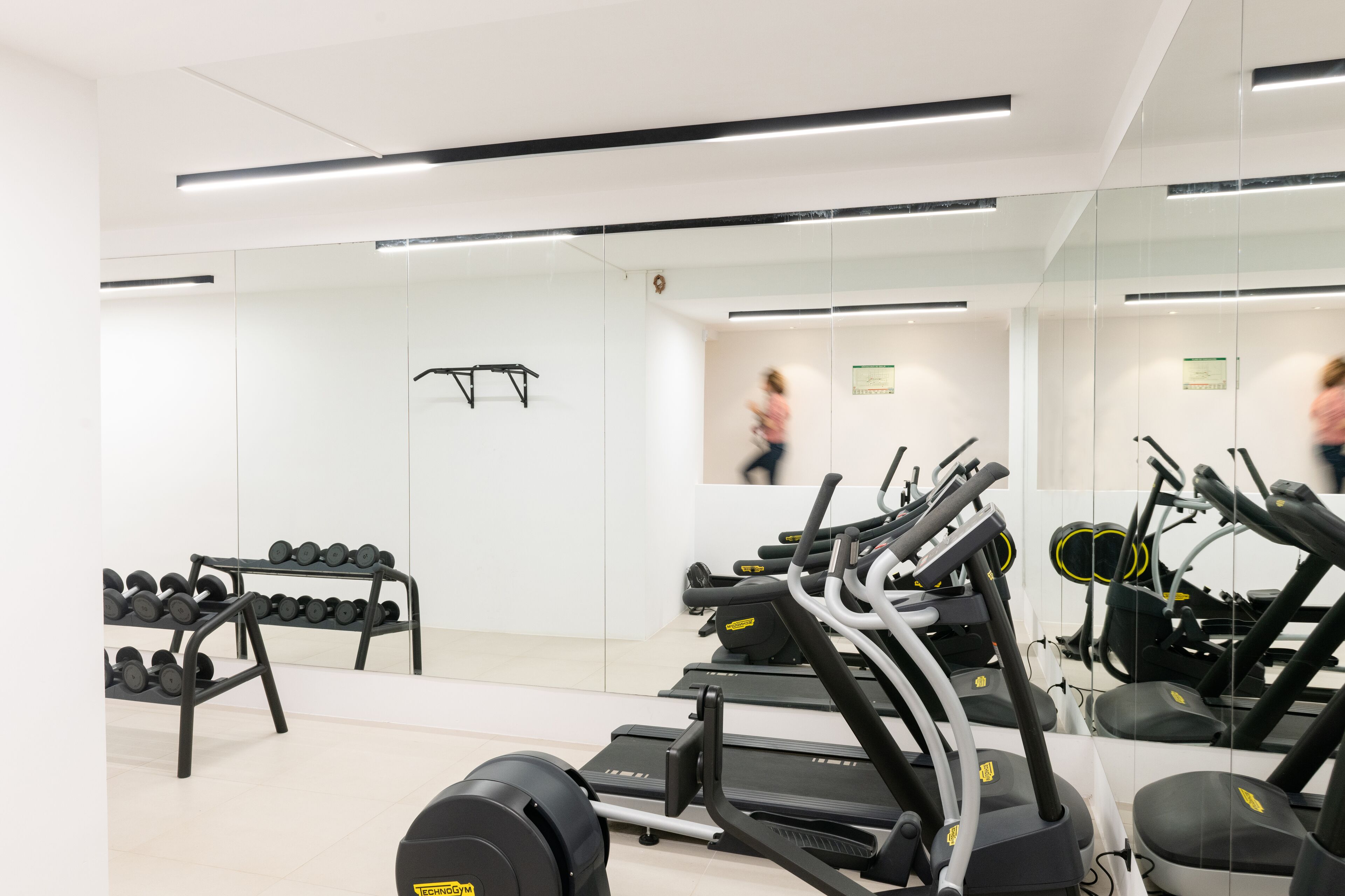A gym with exercise equipment, weight racks, and a large mirror.