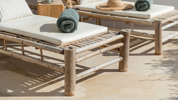 A sunlit outdoor seating area with two lounge chairs, a woven umbrella, and a small table with a cup. - The Olive Boutique Suites and Spa (Santa Eulalia del Rio)