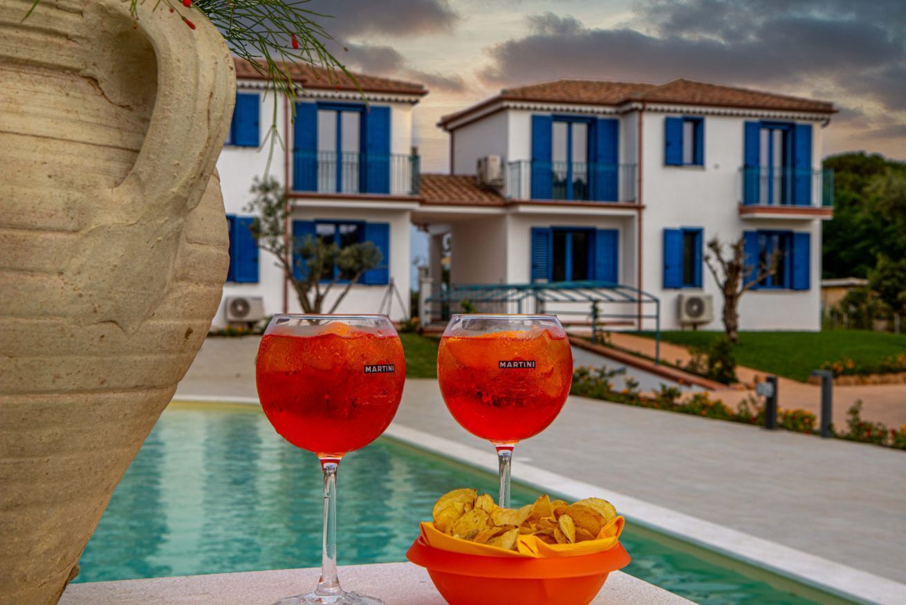 Escena junto a la piscina con dos vasos de Martini y un cuenco de patatas fritas.
