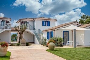 A two-story house with a patio, a staircase, and a garden area.