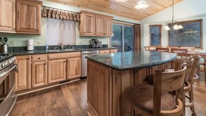 Una cocina con armarios de madera, una isla central y un comedor con sillas de madera.