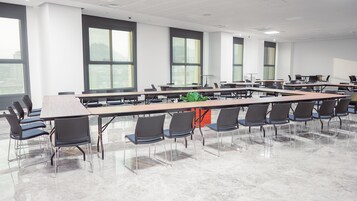 Un salón de conferencias con largas mesas y sillas, amplias ventanas y un diseño moderno.