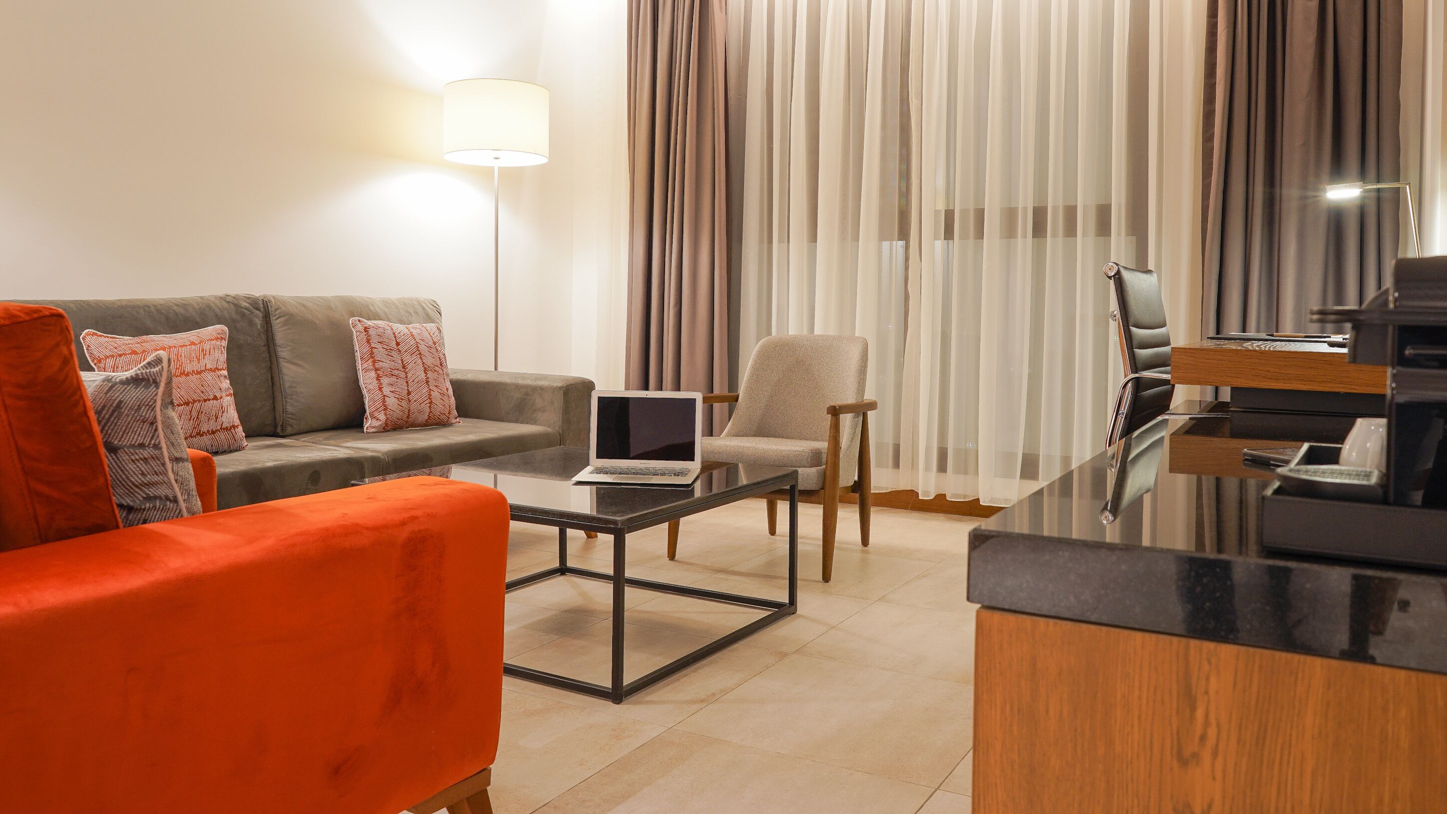 Una sala de estar moderna con un sofá, un sillón y una mesa de centro con una computadora portátil.