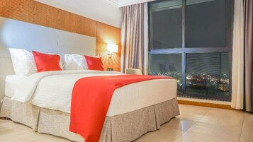 Habitación de hotel con una cama grande, vistas a la ciudad a través de la ventana y un diseño moderno con un revestimiento de pared de madera.