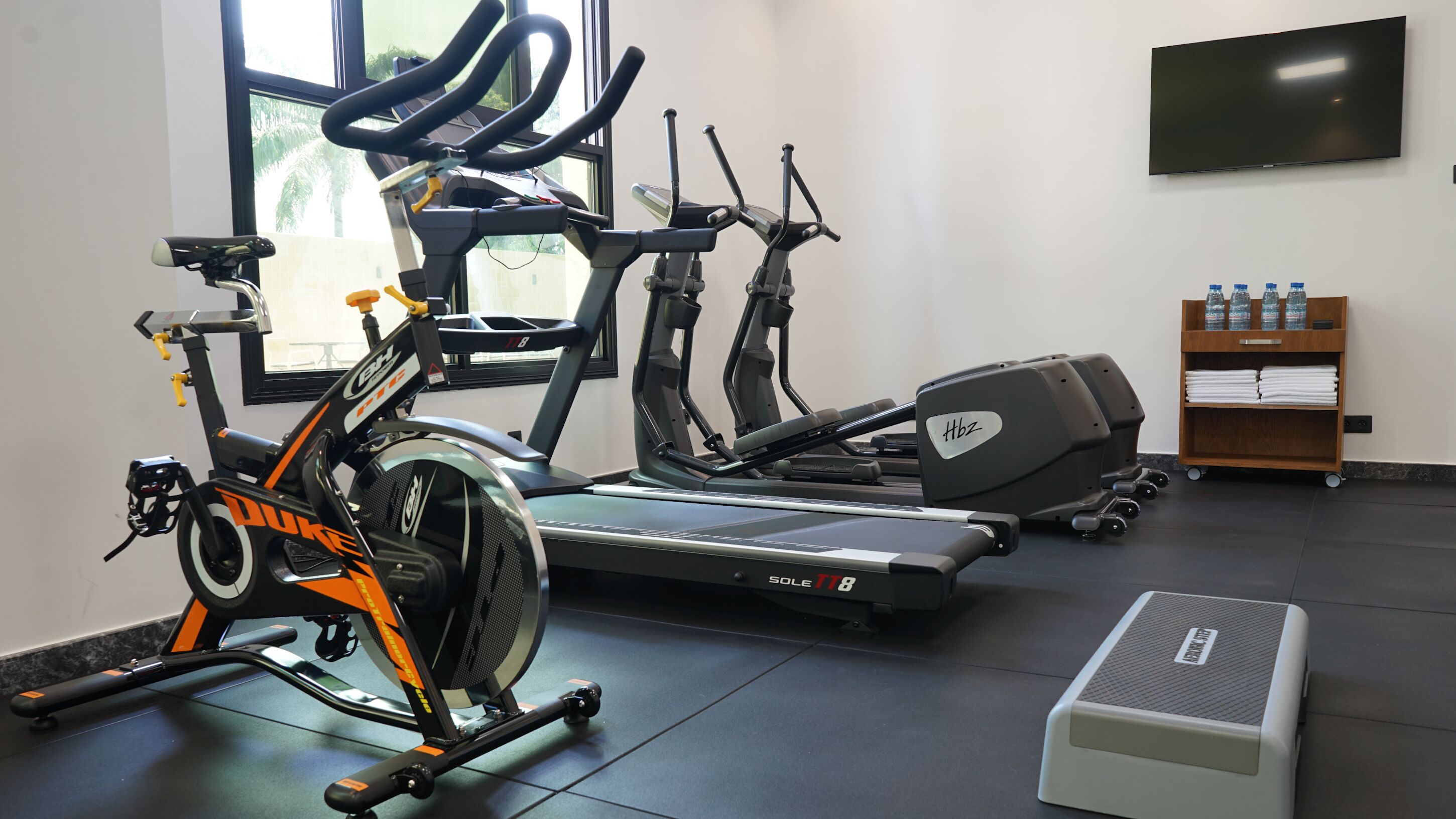 A gym with stationary bikes, treadmills, and a step platform.