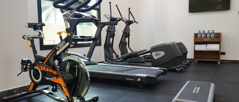 A gym with stationary bikes, treadmills, and a step platform.