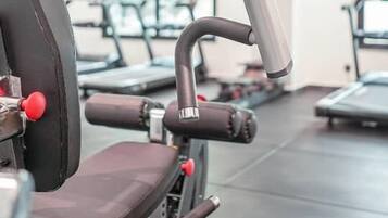 Une salle de sport équipée de matériel d’exercice, notamment une machine à presses pour les jambes et un banc.