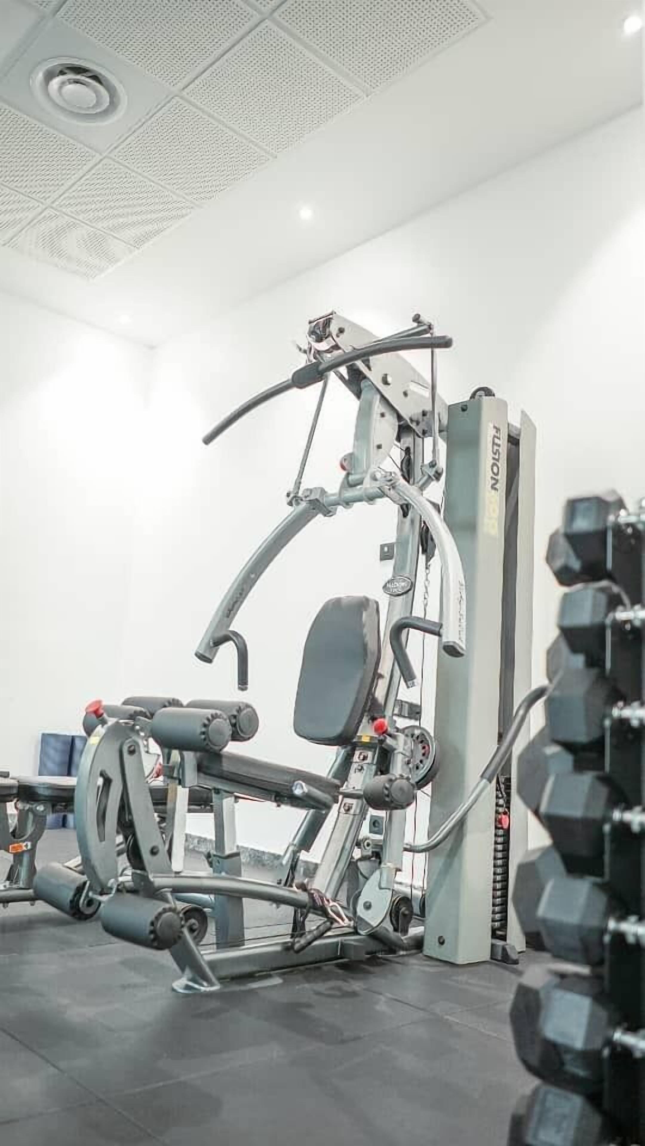 A gym with a variety of exercise equipment, including a weight bench and dumbbells.